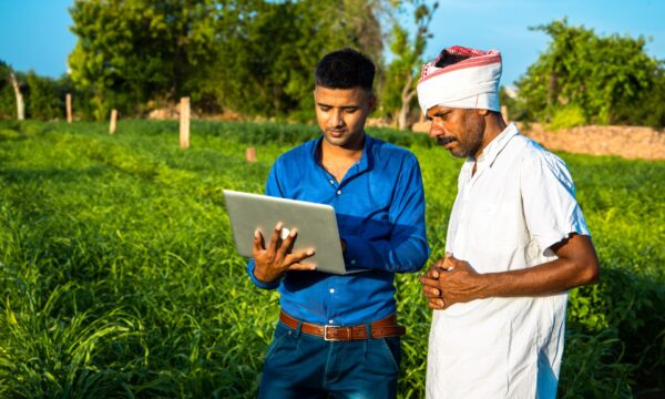 Two farmers look at data on a tablet.