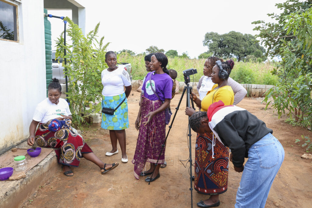 Women filming in front of house and fields