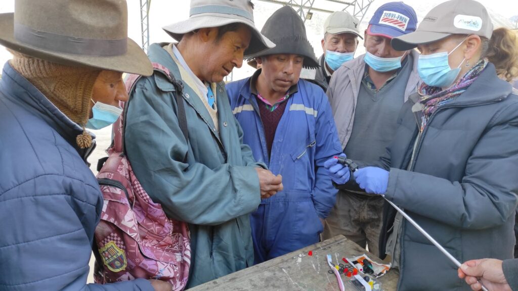 A woman instructor demonstrates the placement of nozzles on pesticide appliances in Ecuador.