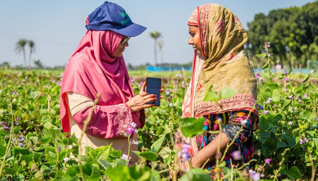 A female agricultural advisors shows a farmer a mobile phone